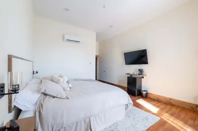 a bedroom with a white bed and a tv at Courtyard King - Room 4 in Versailles