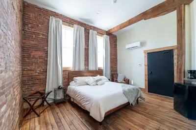 a bedroom with a bed and a brick wall at ADA Suite - Room 6 in Versailles