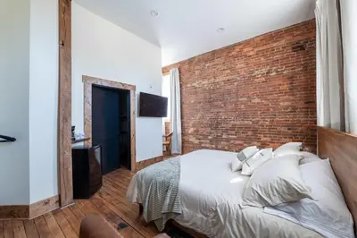 a bedroom with a brick wall and a bed at ADA Suite - Room 6 in Versailles