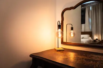 a lamp on a table in front of a mirror at ADA Suite - Room 6 in Versailles