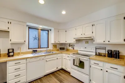 a white kitchen with white cabinets and a window at 1 Mi to Freer Field Ashland Home with Yard! in Ashland