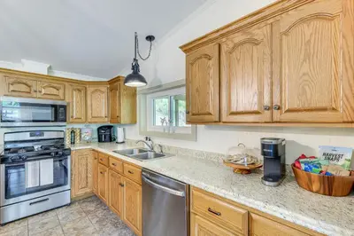 a kitchen with wooden cabinets and stainless steel appliances at Walk to River Loudonville Retreat with Hot Tub! in Loudonville