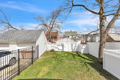 a white fence in front of a white house at Cozy Getaway with Hot Tub, Patio & Fenced Yard home in Garfield Heights