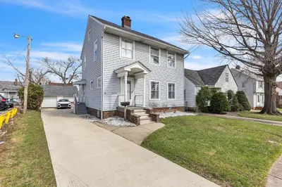 a white house with a driveway in front of it at Cozy Getaway with Hot Tub, Patio & Fenced Yard home in Garfield Heights