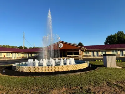 a fountain in the grass in front of a building at Four Seasons Inn in Gallipolis