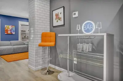 a bar with an orange chair in a room at Tremont Jewel Group Stay in the Heart of Tremont in Cleveland