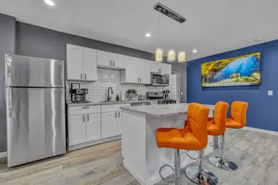 a kitchen with white cabinets and orange bar stools at Tremont Jewel Group Stay in the Heart of Tremont in Cleveland