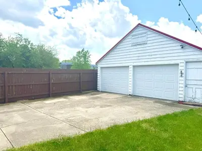 a garage with white doors and a fence at Sleep with a Lion!! 6 bedroom house, near downtown, Ohio city Tremont! in Cleveland