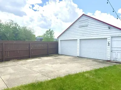a garage with white doors and a fence at Sleep with a Lion!! 6 bedroom house, near downtown, Ohio city Tremont! in Cleveland
