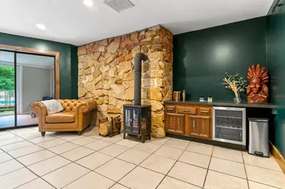 a living room with a fireplace and a stone wall at The Billy Lodge in Lucas