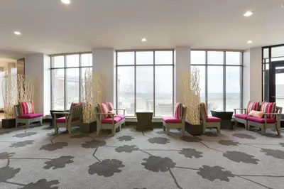 a waiting room with chairs and tables and windows at Hilton Garden Inn Pittsburgh Airport South-Robinson Mall in Robinson Township