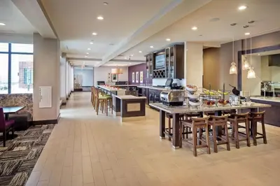 a large kitchen with wooden tables and chairs at Hilton Garden Inn Pittsburgh Airport South-Robinson Mall in Robinson Township