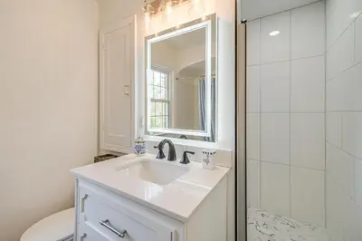 a white bathroom with a sink and a mirror at Historic University Heights Home with Private Yard! in University Heights