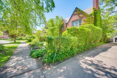 a house with green bushes on the side of a sidewalk at Historic University Heights Home with Private Yard! in University Heights