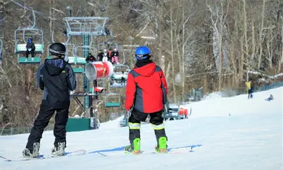 two people standing on a ski lift in the snow at Oglebay Resort in Wheeling