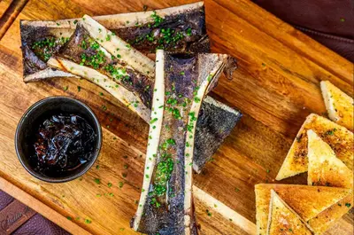 a wooden cutting board with a sandwich and a bowl of dips at Oglebay Resort in Wheeling