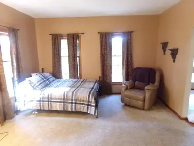a bedroom with a bed and a chair and windows at Family Friendly lodge located in the Hocking Hills in Rockbridge