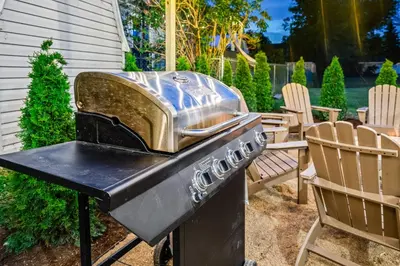 a grill sitting in a yard with two chairs at Cedar Point, Kalahari, Sports Force, Hot tub, Fire pit, EV, Pets, Beach, Fireplace, Park in Huron