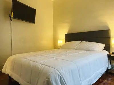 a bedroom with a white bed and a flat screen tv at Cozy room in 2nd floor - near Airport & Lakewood in Cleveland