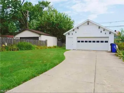 a white garage with a driveway in a yard at Cozy room in 2nd floor - near Airport & Lakewood in Cleveland