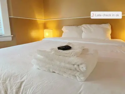 a bed with towels on it with a sign that says take check in ok at Puro Cuarto | Room 10 min Downtown, 15 to Airport in Cleveland