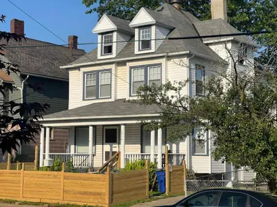a white house with a wooden fence in front of it at Puro Cuarto | Room 10 min Downtown, 15 to Airport in Cleveland