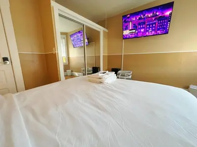 a bedroom with a large white bed with a tv on the wall at Puro Cuarto | Room 10 min Downtown, 15 to Airport in Cleveland