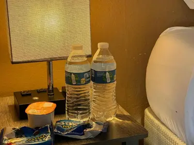 two bottles of water on a table next to a lamp at Puro Cuarto | Room 10 min Downtown, 15 to Airport in Cleveland
