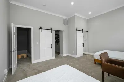 a bedroom with white walls and a bed and a chair at Cincy Comfort Retreat in Cincinnati