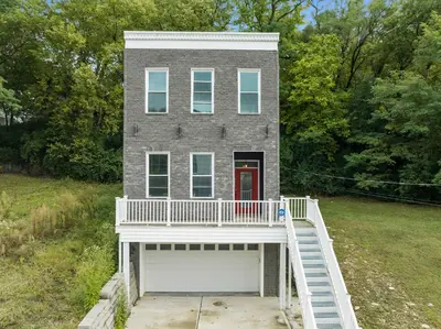 a gray house with a white porch and a white balcony at Cincy Comfort Retreat in Cincinnati