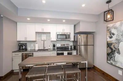 a kitchen with white cabinets and a stainless steel refrigerator at Luxury Mt Adams Retreat Apt 1 in Cincinnati