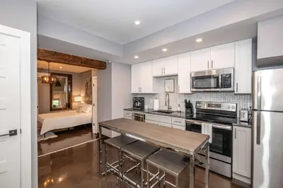 a kitchen with white cabinets and a table and a bed at Luxury Mt Adams Retreat Apt 1 in Cincinnati