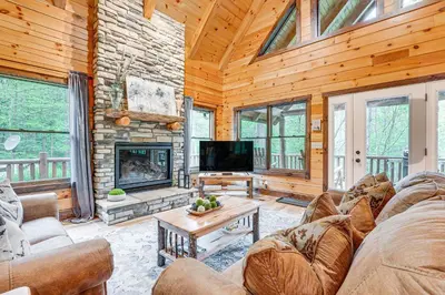 a living room with a stone fireplace in a log cabin at 15 Mi to Hocking Hills Secluded Cabin with Hot Tub in Logan