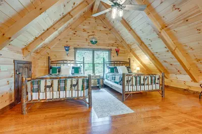 a bedroom with two beds in a log cabin at 15 Mi to Hocking Hills Secluded Cabin with Hot Tub in Logan