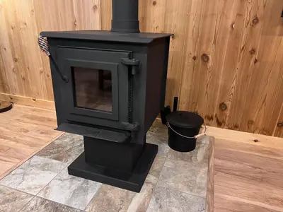 a black stove with a trash can in a room at Burton Ridge Cabin in South Bloomingville