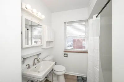 a white bathroom with a toilet and a sink at The Grand Elm Suites in Ludlow