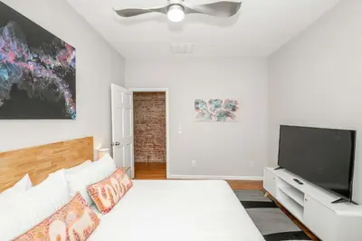 a white bedroom with a bed and a flat screen tv at Sweet Escape in Cincinnati