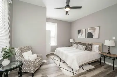 a bedroom with a bed and a chair and a ceiling fan at Queen City Grand House in Cincinnati