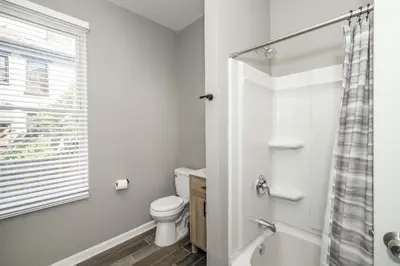 a white bathroom with a toilet and a window at Queen City Grand House in Cincinnati