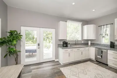 a white kitchen with white cabinets and a table at Queen City Grand House in Cincinnati