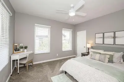 a bedroom with a bed and a desk and windows at Queen City Grand House in Cincinnati