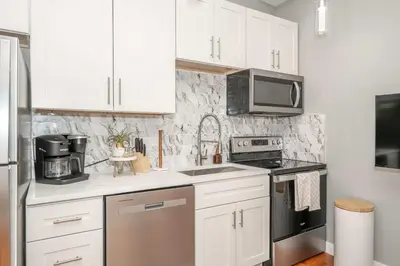 a kitchen with white cabinets and a sink and a microwave at Findlay Market - Suite 4 for 2 in Cincinnati