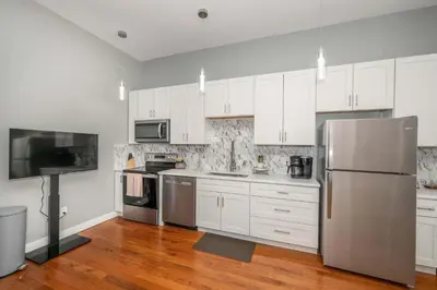 a kitchen with white cabinets and a stainless steel refrigerator at Findlay Market - Suite 5 for 2 in Cincinnati