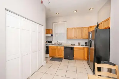a kitchen with wooden cabinets and a black refrigerator at Hackberry Retreat 1 Close to Downtown in Cincinnati
