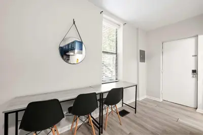 a dining room table with chairs and a clock on the wall at The Luxe Pearl Residences in Columbus