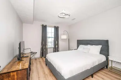 a white bedroom with a bed and a television at Arkstone Retreat 1 - Chic Downtown Escape in Williamstown