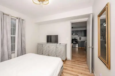 a white bedroom with a bed and a mirror at Arkstone Retreat 1 - Chic Downtown Escape in Williamstown