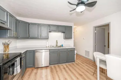 a kitchen with gray cabinets and a ceiling fan at Arkstone Retreat 1 - Chic Downtown Escape in Williamstown