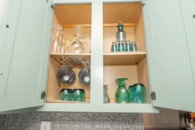 a kitchen cabinet filled with glass vases and dishes at Arkstone Retreat 2 - Chic 2 Bedroom in Williamstown