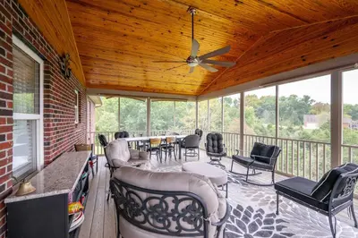 a screened in porch with chairs and a ceiling fan at Lazy Days Waterfront for 12 in Williamstown